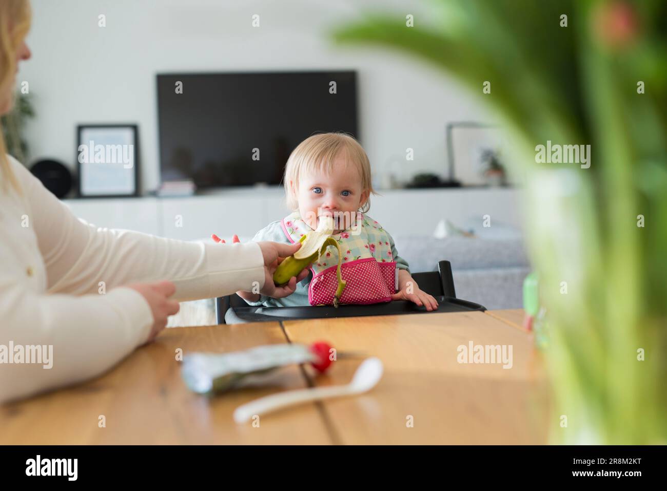 Toddler with down syndrome sitting at table Stock Photo