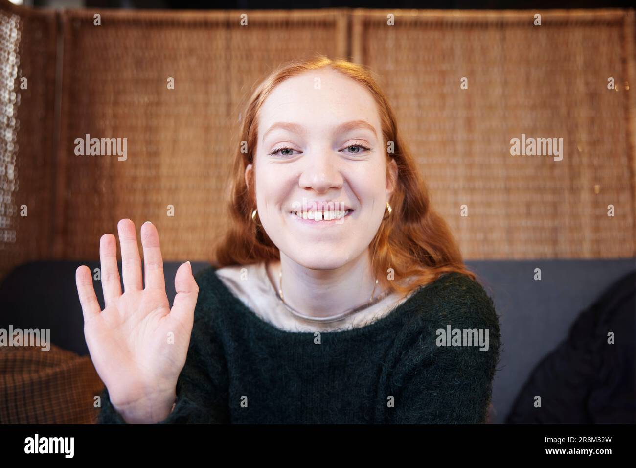 Portrait of smiling woman looking and waiving at camera Stock Photo