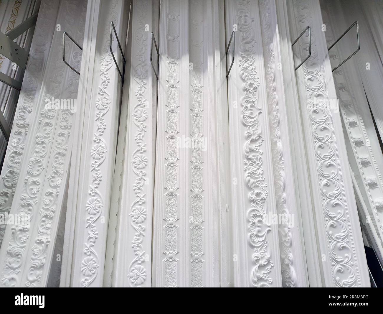 ceiling cornices, different types of white foam plastic ceiling moldings at store showcase, demonstration stand samples, showroom Stock Photo