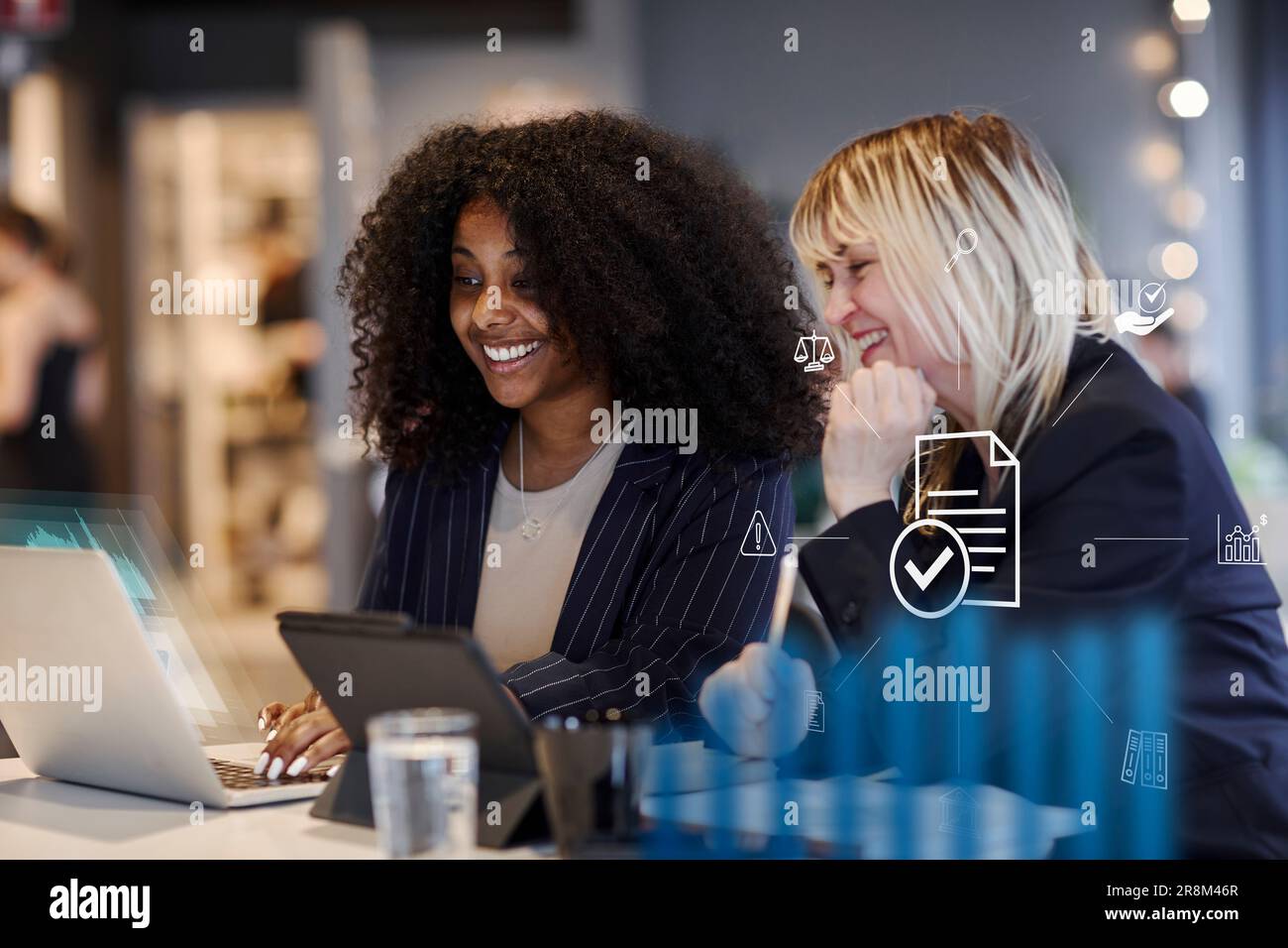 Smiling women in office using laptop together Stock Photo