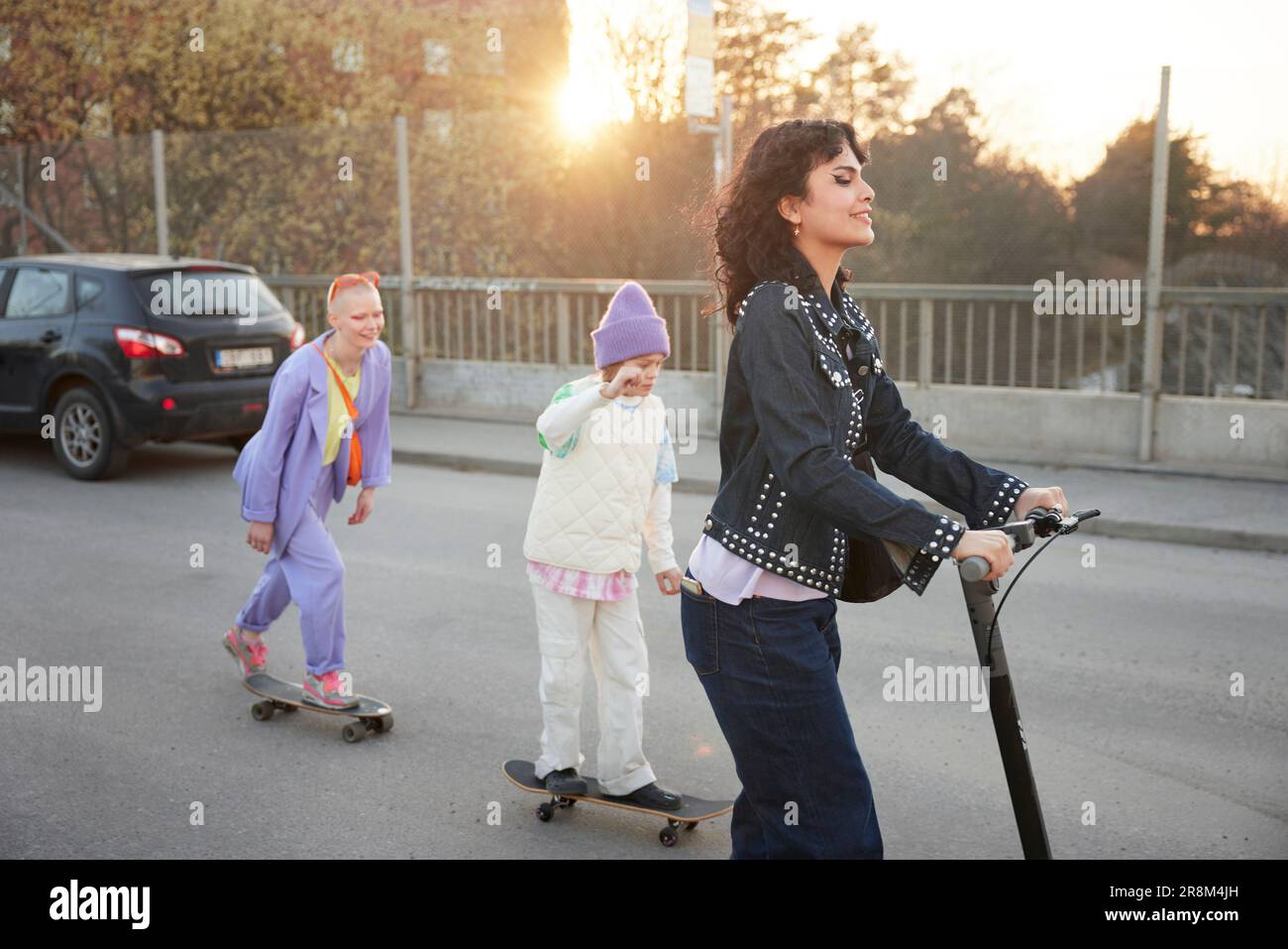 Young women and boy skateboarding together Stock Photo