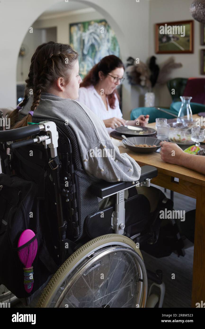 Father and disabled teenage girl sitting and dining table and having