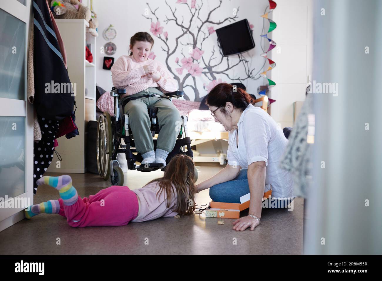 Mother and daughter doing jigsaw puzzle, disabled teenage daughter in