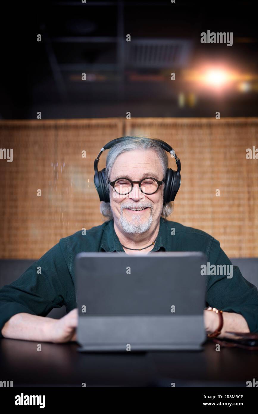 Smiling senior man with headphones using tablet Stock Photo