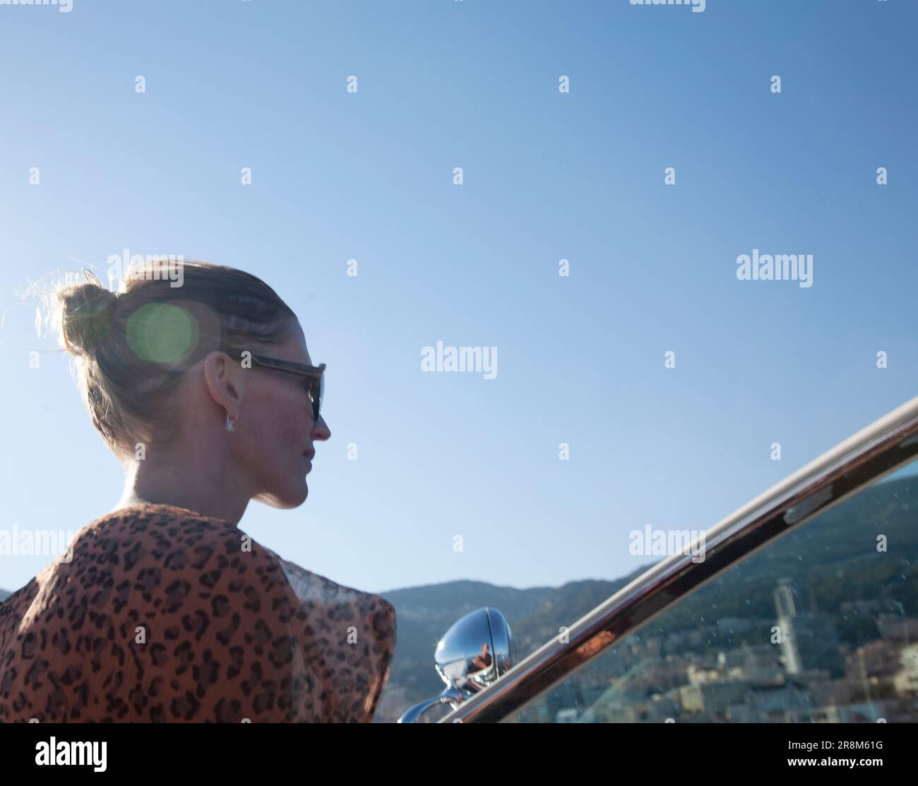 Woman in sunglasses looking forward while driving boat, lens flair Stock Photo