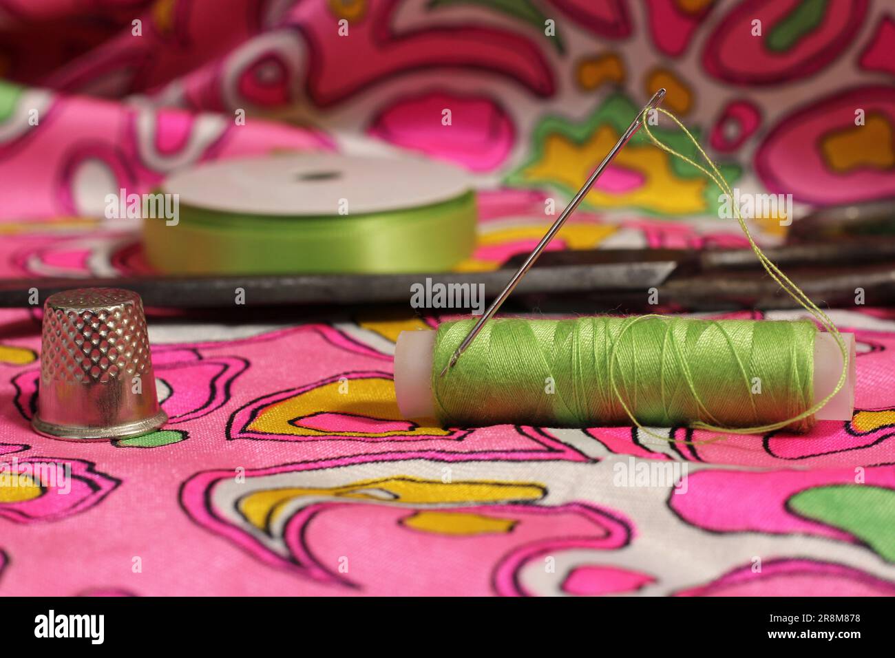 Spool of green thread and needle Stock Photo - Alamy