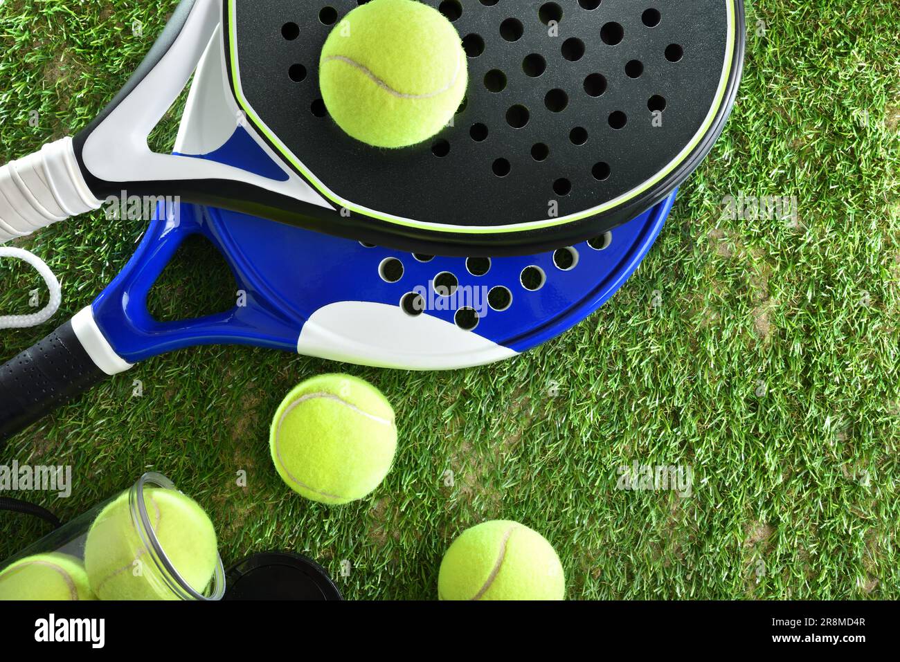 Two paddle tennis rackets and a can of balls on artificial grass. Top