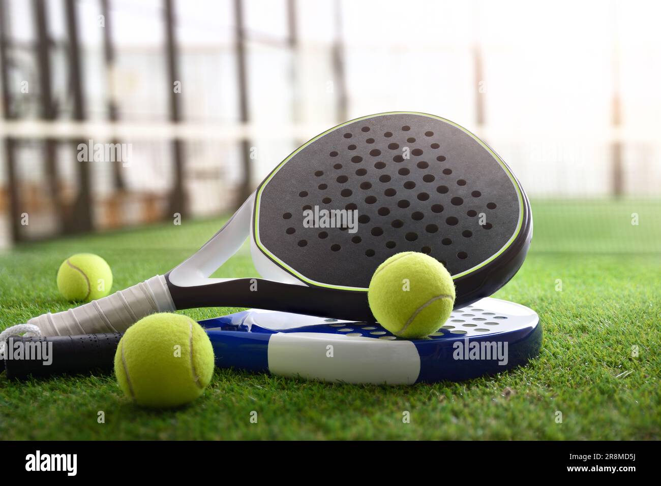 Padel rackets and balls on artificial grass floor in outdoor court. Front view. Stock Photo