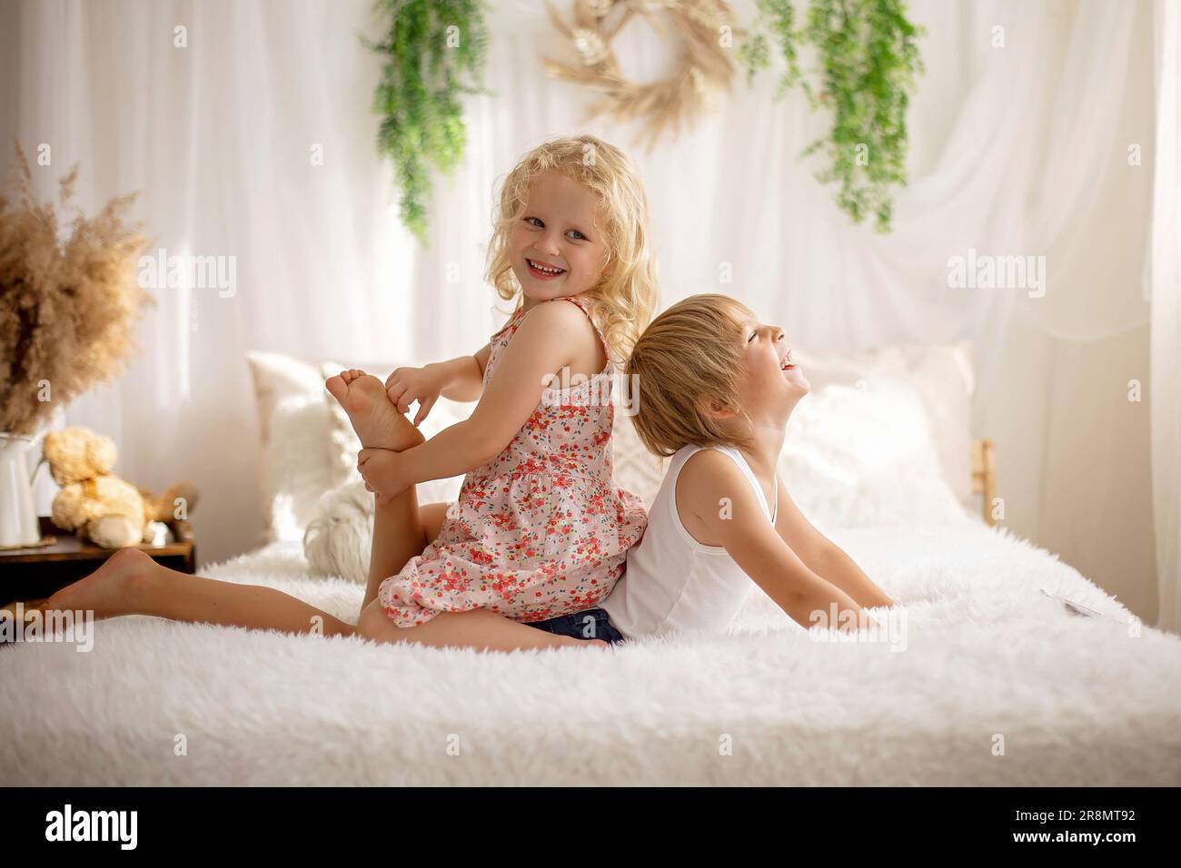 Cute sweet toddler children, tickling feet on the bed, laughing and smiling, childish mischief, happiness Stock Photo