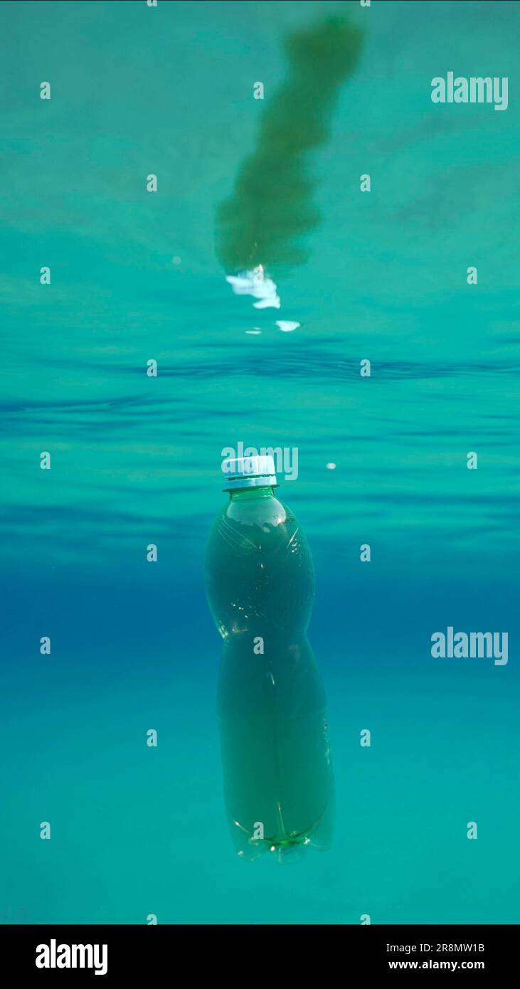 Green plastic bottle drifting under surface of blue water. Plastic
