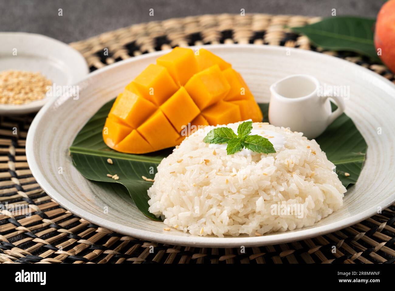Delicious Thai mango sticky rice with cut fresh mango fruit in a plate on gray table background. Stock Photo