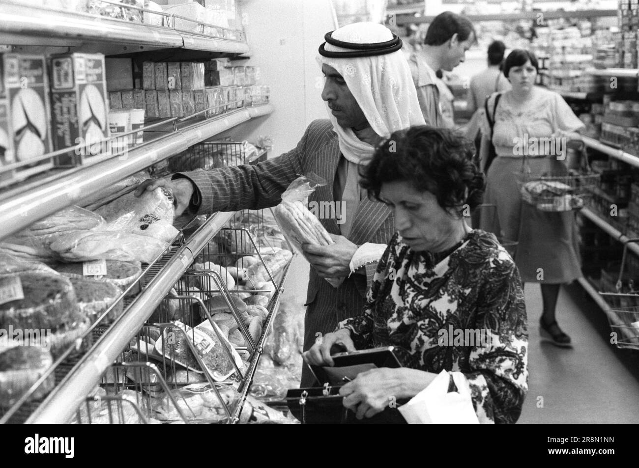 Poor Arabs in London Food Shopping 1970s UK . During the late 1970s Middle Eastern governments provided healthcare for their nationals in London, many stayed in bedsit cheap accommodation in the Earls Court area. A couple grocery shopping the man is buying Pita is a flatbread. Earls Court, London, England circa 1977 70s HOMER SYKES Stock Photo