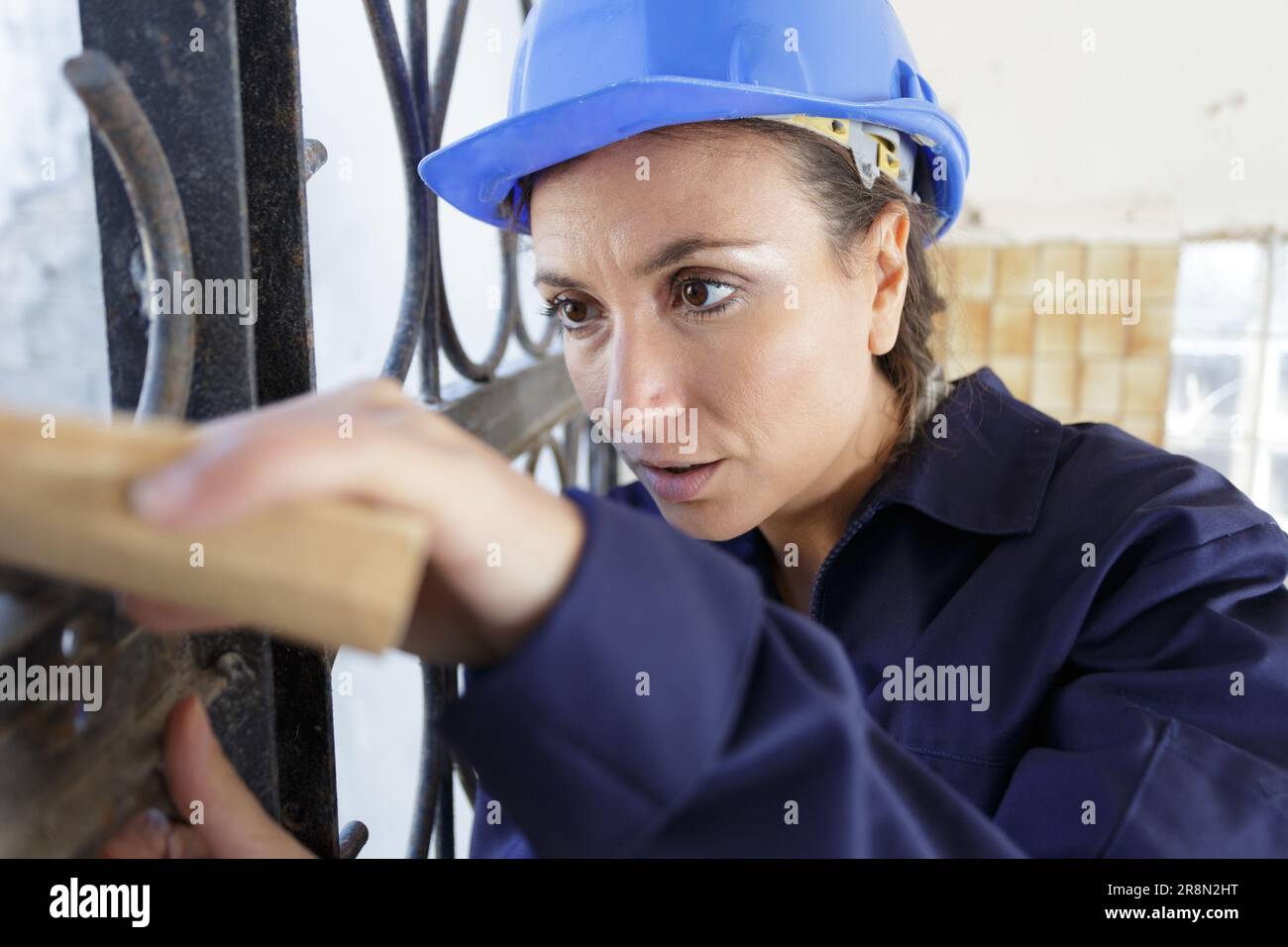 female builder sanding metal fence Stock Photo Alamy