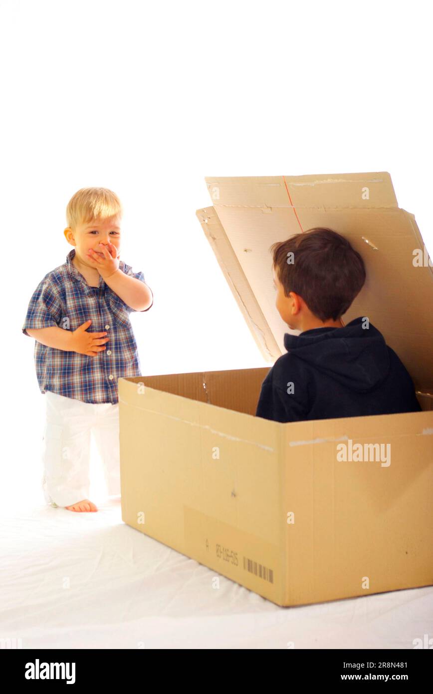 Boy in cardboard box, frightens toddler, frighten, surprise, surprise Stock Photo