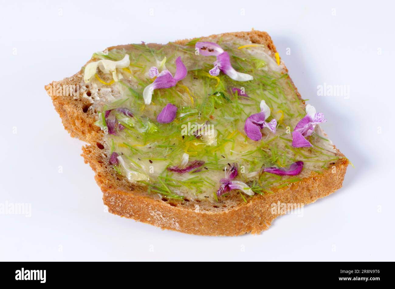 Slice of bread with flower honey, common spruce (Picea abies), fresh tips, loosestrife flowers, spotted (Lamium maculatum) dead-nettle flowers, white Stock Photo