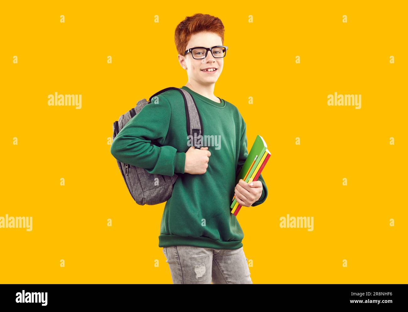 Smiling handsome teenage boy with backpack holding books Stock Photo ...