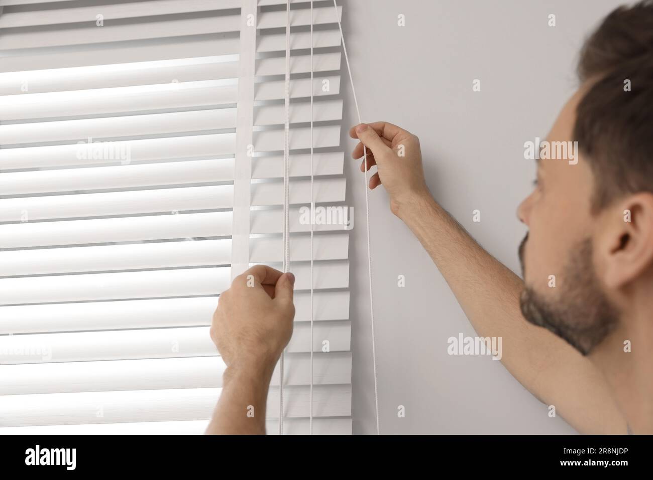 Worker opening or closing horizontal window blind indoors, closeup Stock Photo