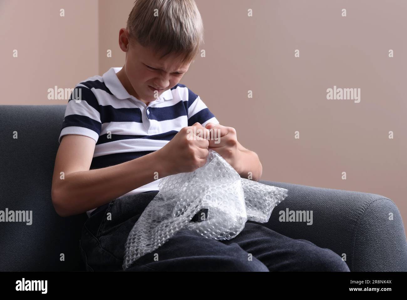 Angry boy popping bubble wrap indoors. Stress relief Stock Photo - Alamy