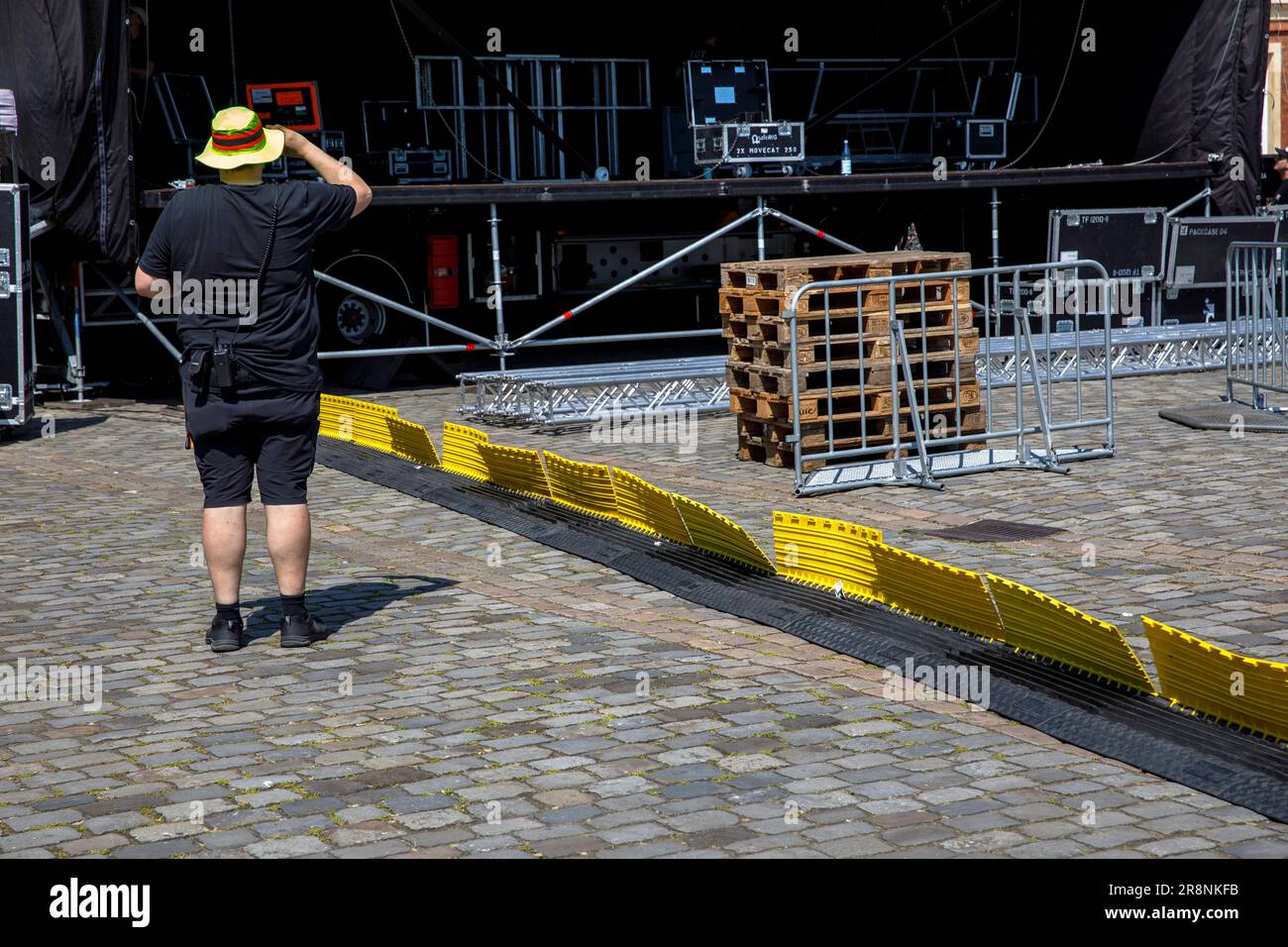 a stagehand with yellow hat and black clothes stands in front of an open-air stage at the castle, black yellow cable cover, Muenster, North Rhine-West Stock Photo