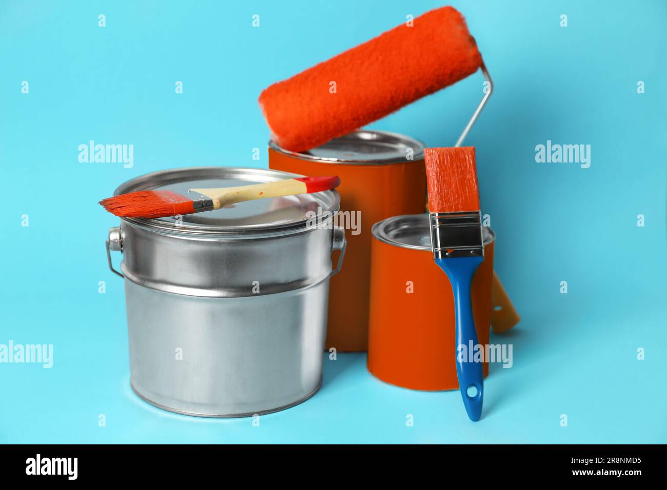 Cans of paint, bucket, roller and brushes on turquoise background Stock