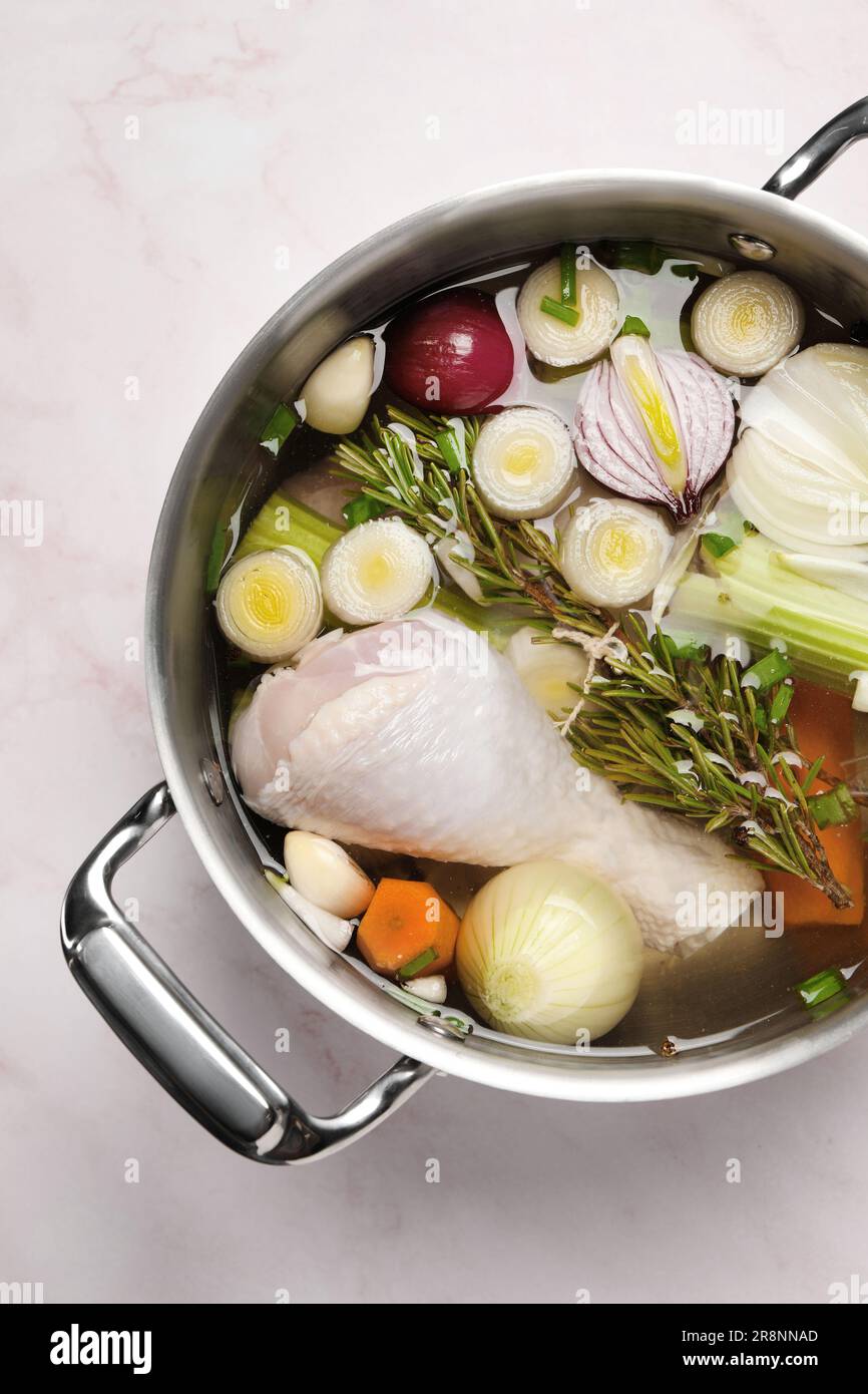 Different ingredients for cooking tasty bouillon in pot on pink marble