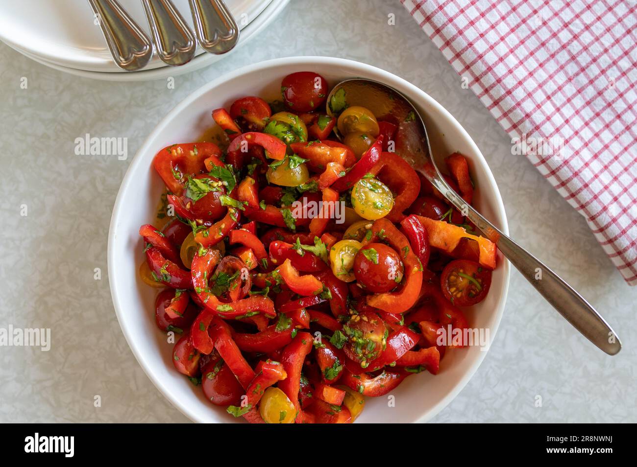 Salad with peppers, red and yellow cherry tomatoes in a bowl with spoon Stock Photo