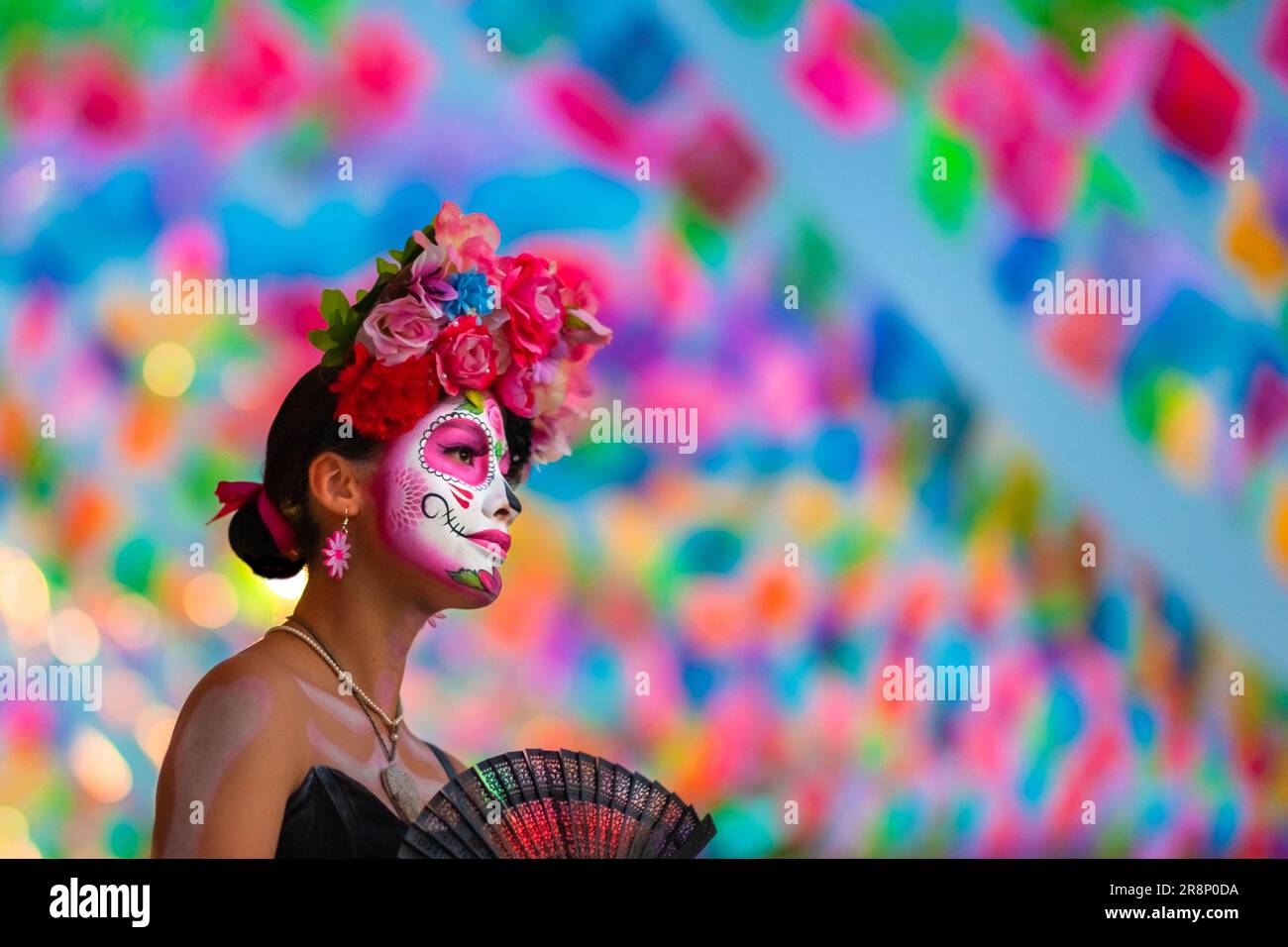 A young Mexican woman, dressed as La Catrina and fanning herself with a handfan, takes part in the Day of the Dead festivities in Tlaquepaque, Mexico. Stock Photo
