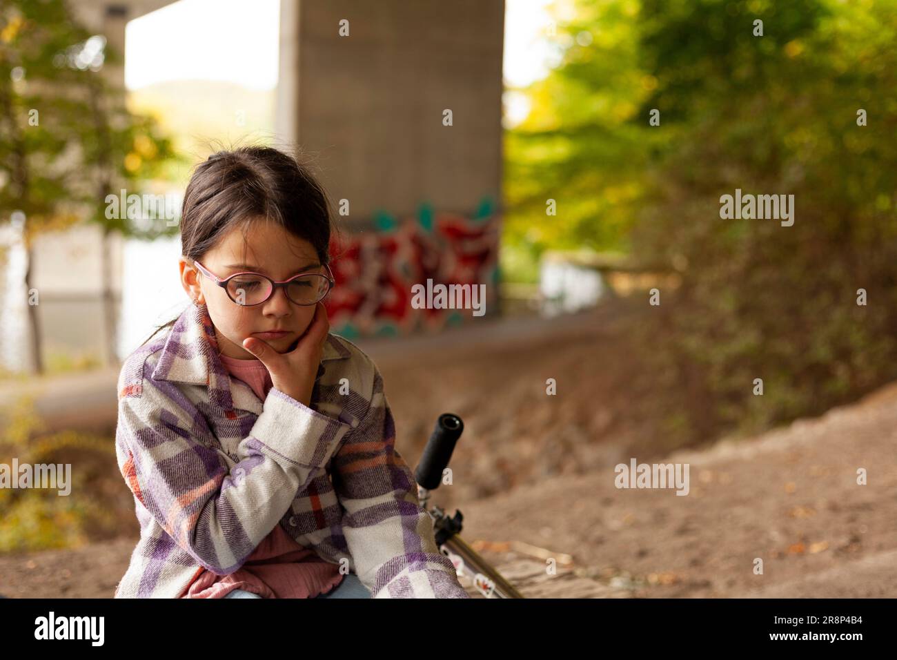 Cute little girl in eyeglasses sitting on the bench in the park Stock ...