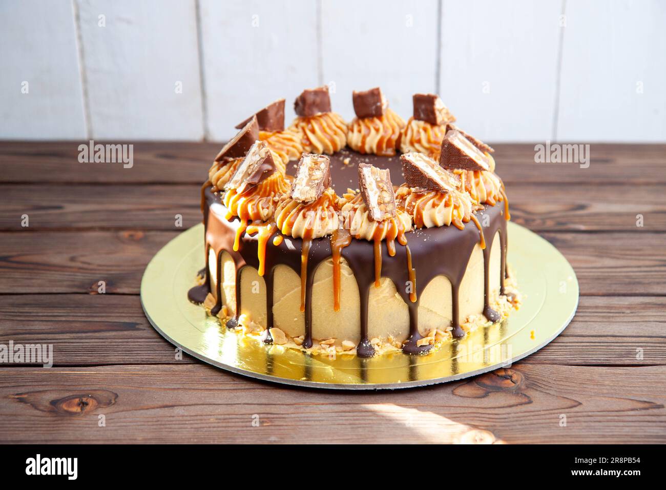 Gorgeous snickers cake with peanut butter cream, melted chocolate, candy bars and salted caramel Stock Photo