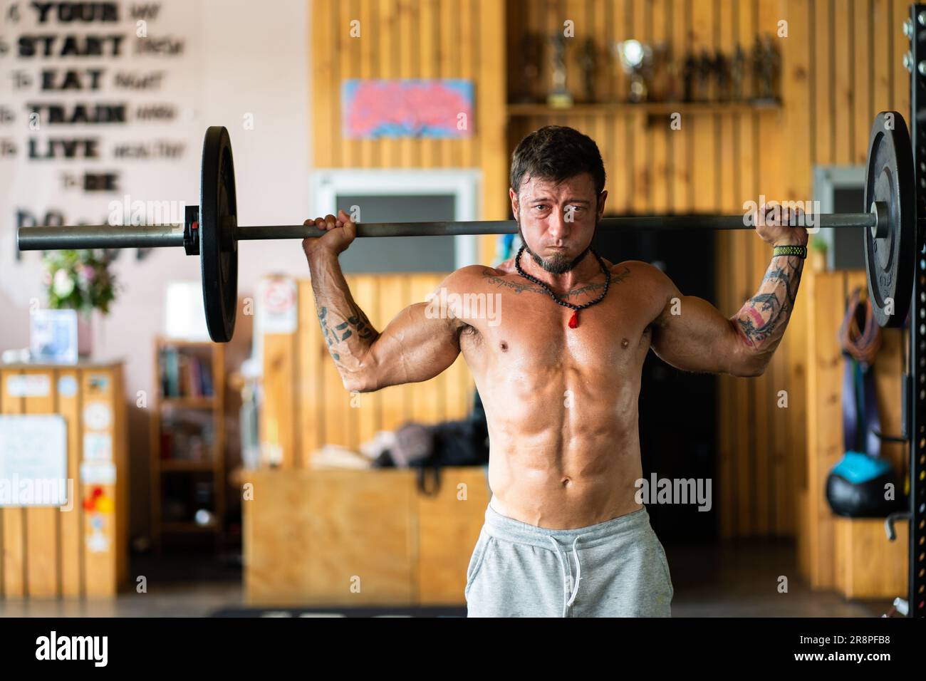 Man doing squats with weight using a bar in a gym Stock Photo