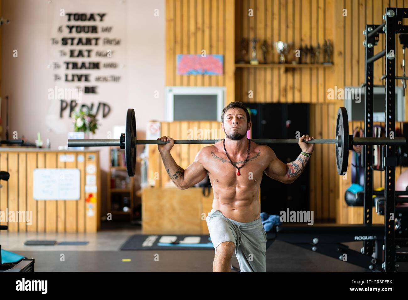 Photo with copy space of a strong man doing squats with weight using a bar in a gym Stock Photo