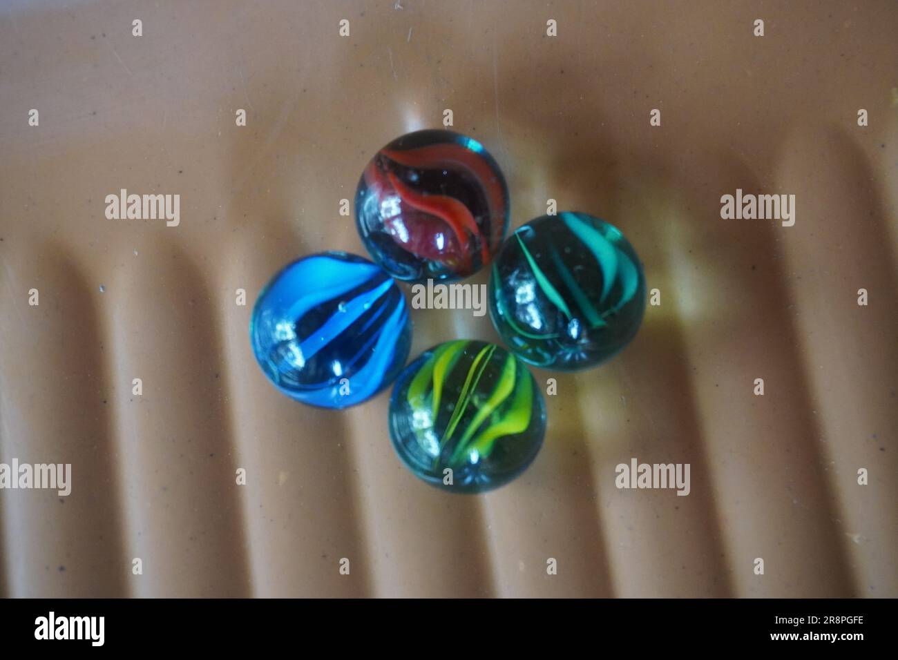 Four different colored marbles are arranged side by side Stock Photo