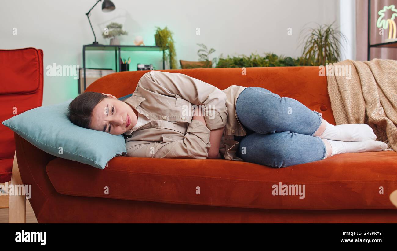 Sick ill woman suffering from painful stomach ache, period cramps lying