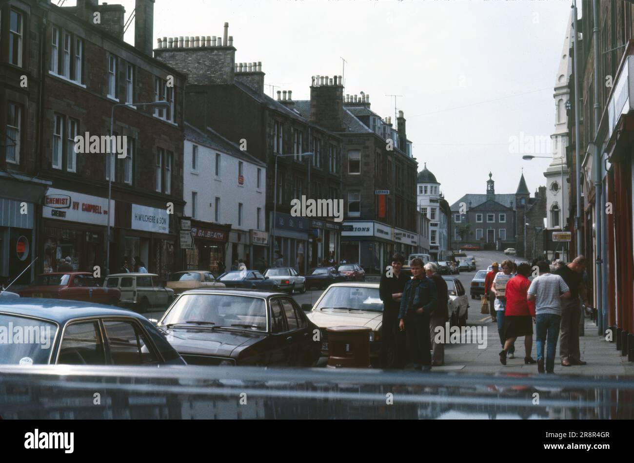 Campbeltown, Scotland, United Kingdom- July 1983: View down Main Street in Campbeltown, vintage cars and shops Stock Photo