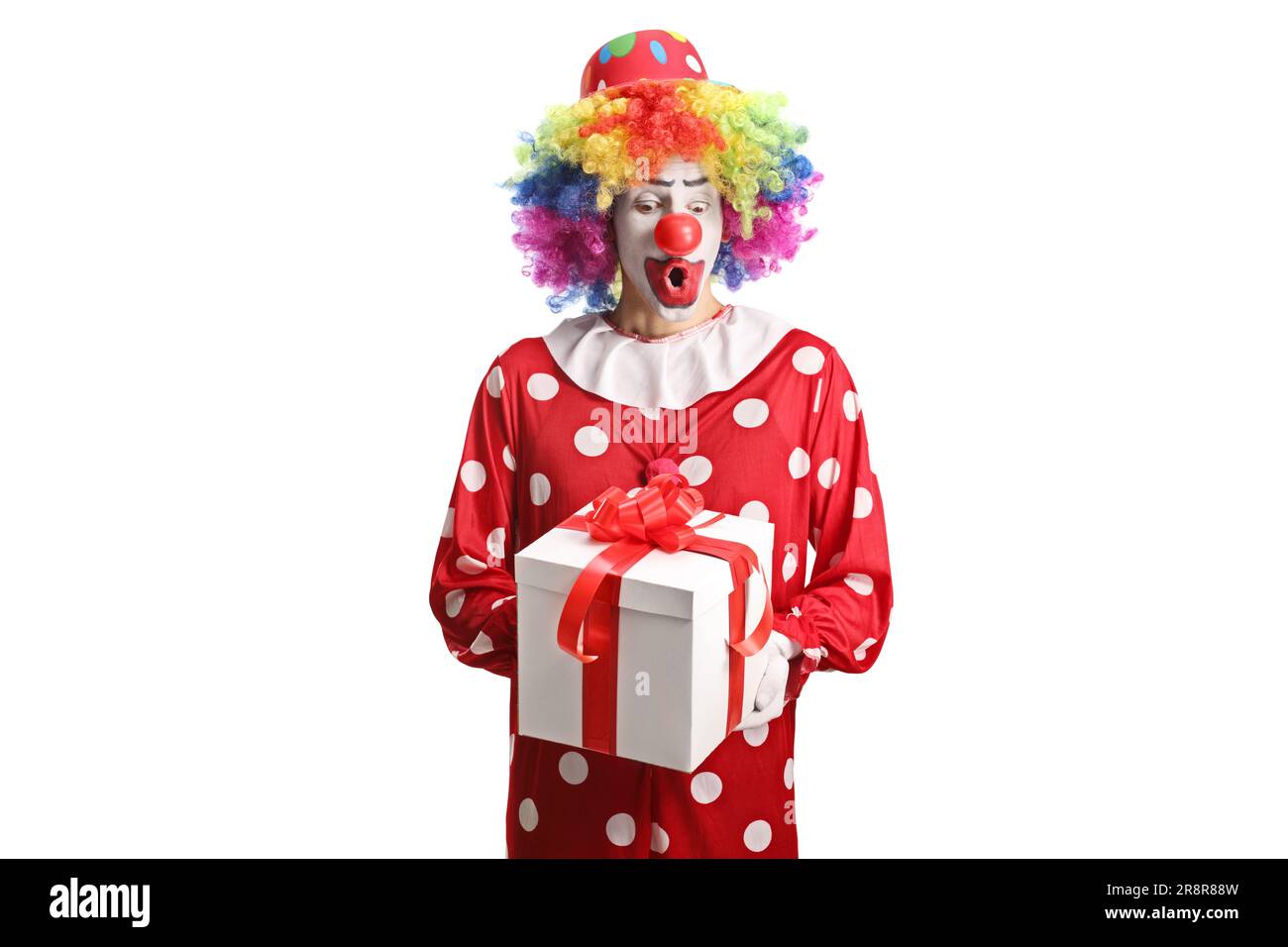 Clown in a red costume holding a present box isolated on white background Stock Photo
