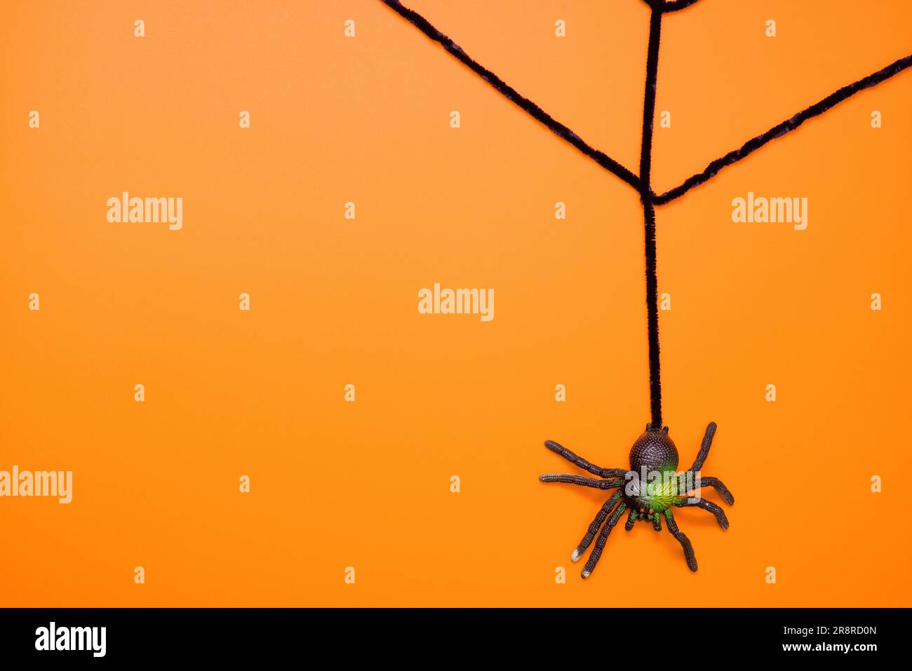 Black toy spider on artificial web on an orange background Stock Photo ...