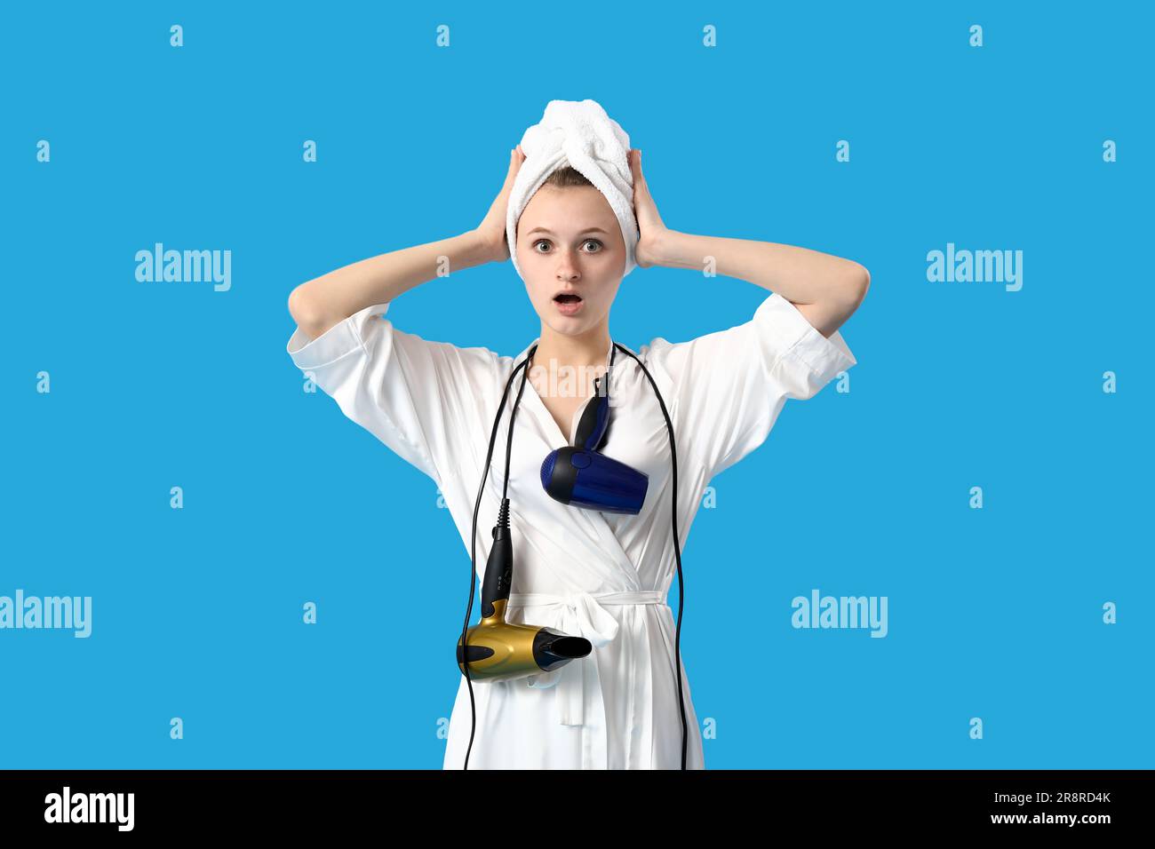 Shocked young woman with hair dryers on blue background Stock Photo Alamy
