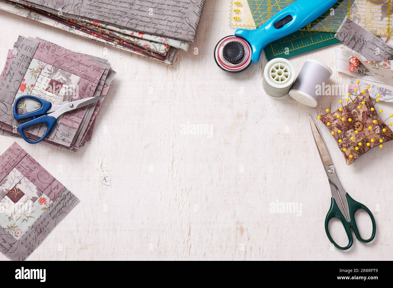 Patchwork log cabin blocks, stack of blocks, sewing accessories on white wooden surface Stock Photo