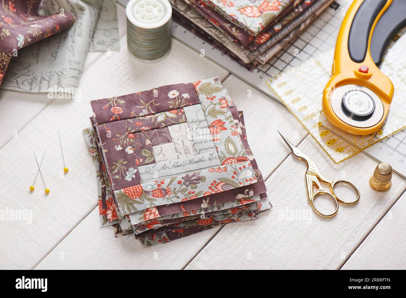 Patchwork log cabin blocks, stack of blocks, sewing accessories on white wooden surface Stock Photo