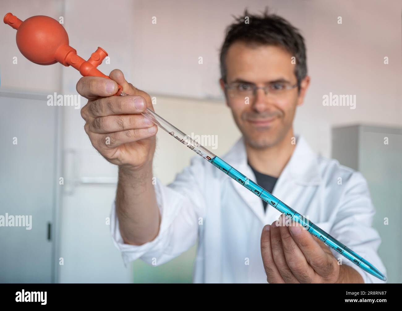Pipette with Peleus ball into chemistry lab. Also called propipet. Chemical scientist in the background Stock Photo