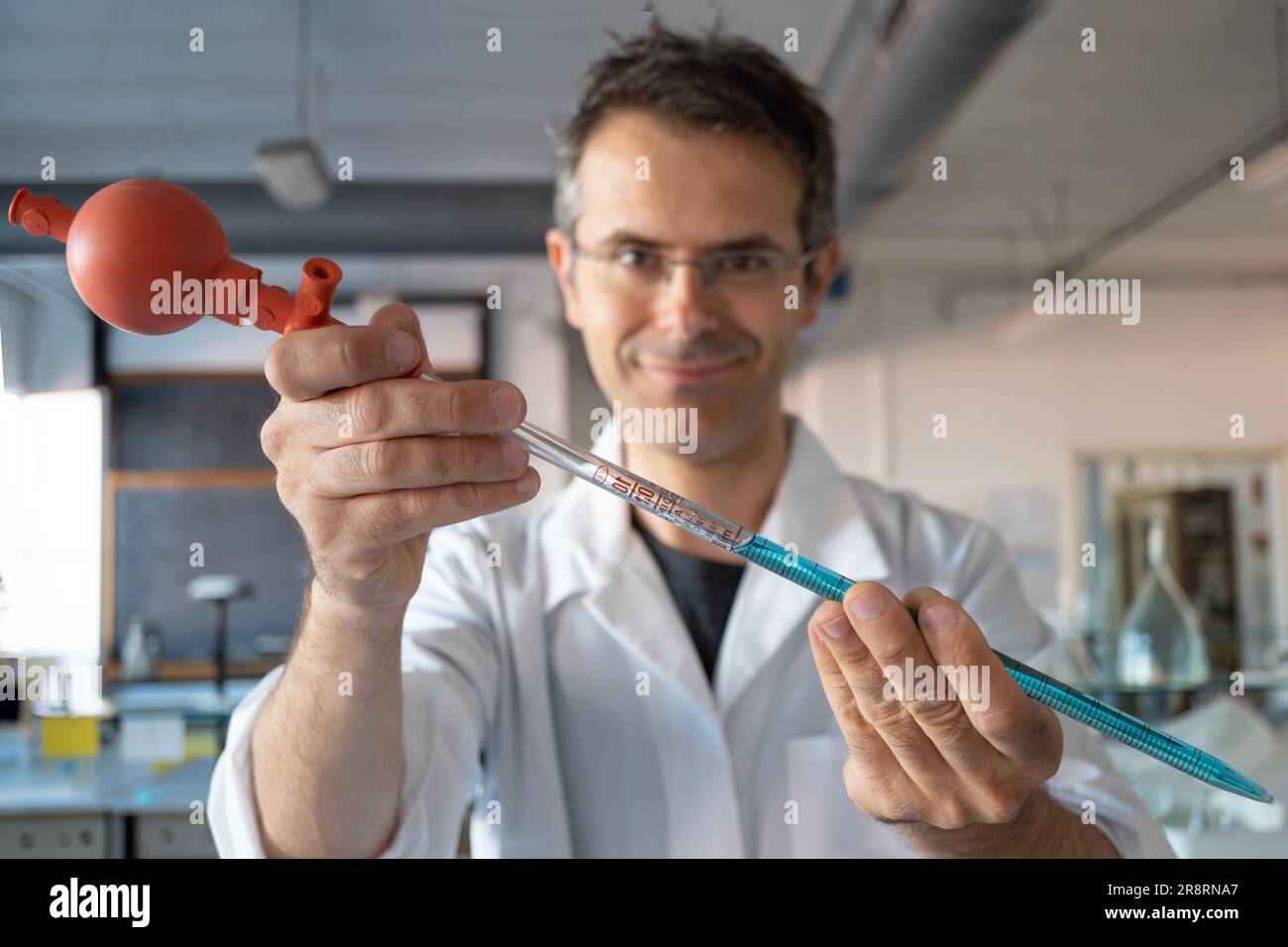 Pipette with Peleus ball into chemistry lab. Also called propipet. Chemical scientist in the background Stock Photo