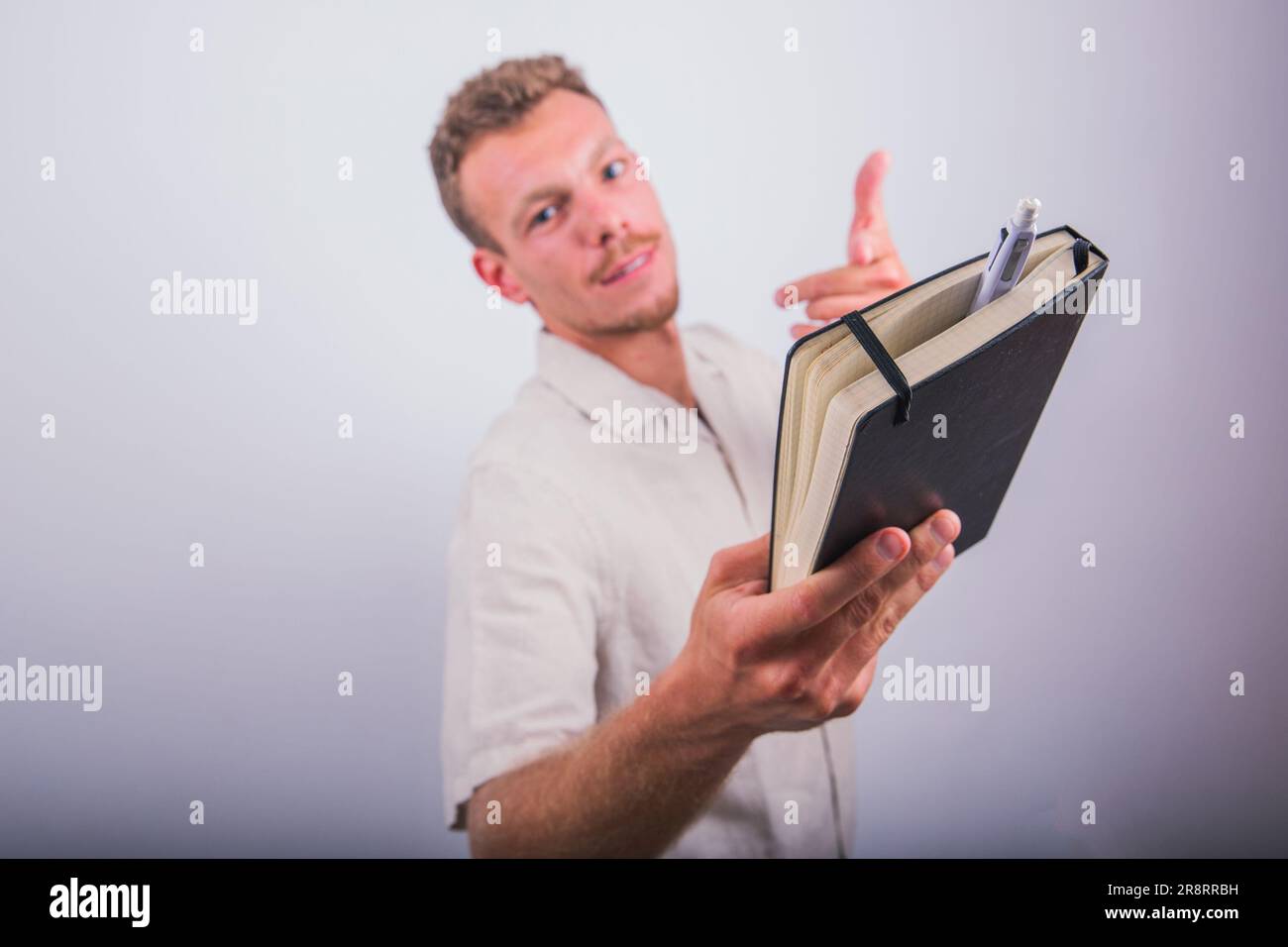A writer holds an agenda and a pen in his hand and points to them, studio shot with white background Stock Photo