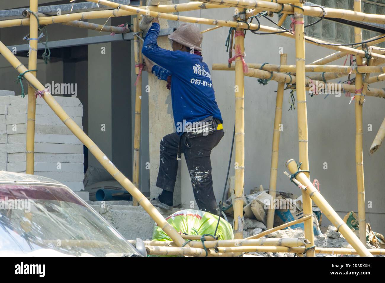 NAN, THAILAND, MAY 19 2023, A worker climbs through bamboo scaffolding at a construction site Stock Photo