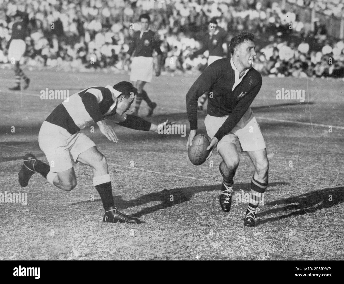 Malcolm Becket, of Natal prepares to tackle fly-half Tate as he sends the ball out to his three-quarters. Australian Rugby Union five-eighth Murray Tate about to get the ball away as Natal player M. Becket comes in for the tackle, during the ***** at Kingsmead. Murray Tate, Union five-eighth, prepares to get the ball away. July 09, 1953. Stock Photo