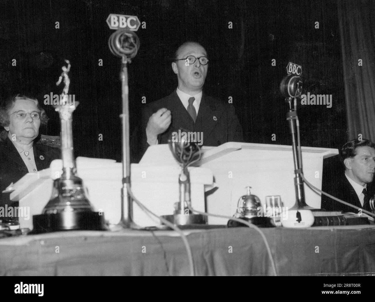 General Secretary Addresses T.U.C. -- Mr. Vincent Tewson (General Secretary of the T.U.C.) addressing delegates at the 80th Trades Union Congress, here. He promised that the General Council would bring the utmost pressure to bear on the Government to secure a progressive reduction on prices and profits. On left is Miss Florence Hancock, Chairman of the T.U.C and right, Mr. Victor Feathers Assistant Secretary, T.U.C. September 10, 1948. (Photo by Planet News). Stock Photo