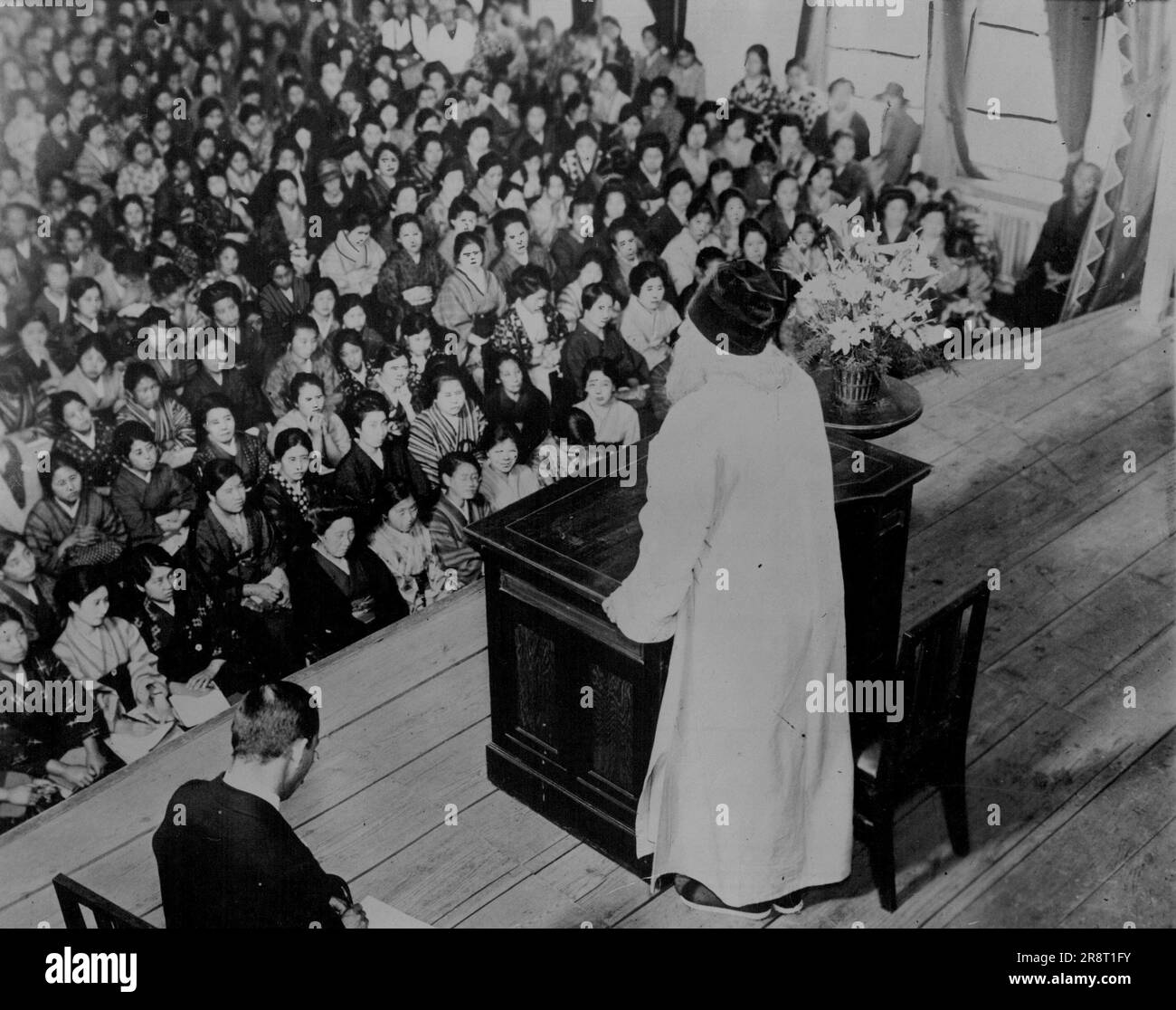 Denouncing The Materialism Of The Western World -- In the foreground, wearing white robe, is shown Dr. Rabindranath Tagore, Indian poet and philosopher, and a 'Warrior Against The West', addressing the women of Tokyo at a special meeting. January 7, 1924. (Photo by International Newsreel). Stock Photo