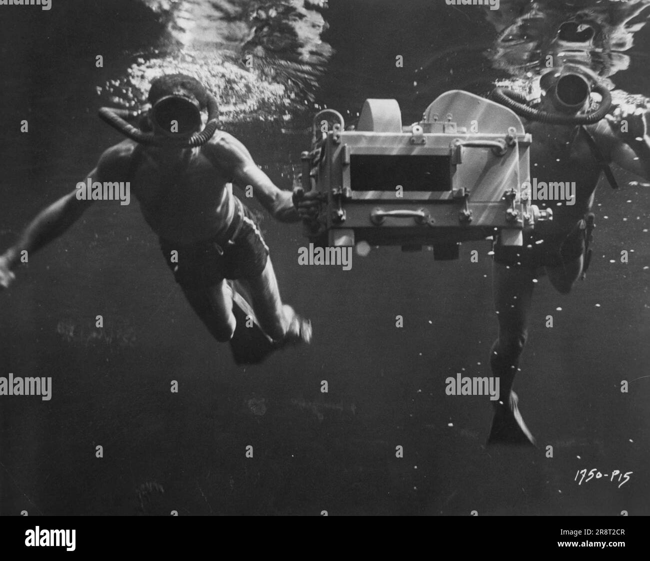 With movie techniques getting as much attention as the movie stars, here's the newest thing 'below the surface' of the Hollywood scene: an underwater 3-D cameral An ingenious gadget devised by Scotty Melbourne, it is shown being moved into underwater position by Melbourne and deep-sea diver Fred Zender at Wakulla Springs, Florida, to shoot scenes for 'Creature From the Black Lagoon.' Universal-International's third-dimensional science-fiction thriller stars Richard Carlson and Julia Adams, and introduces the Gill Man, an amphibian monster who seeks his prey on land and underwater. Januar… Stock Photo