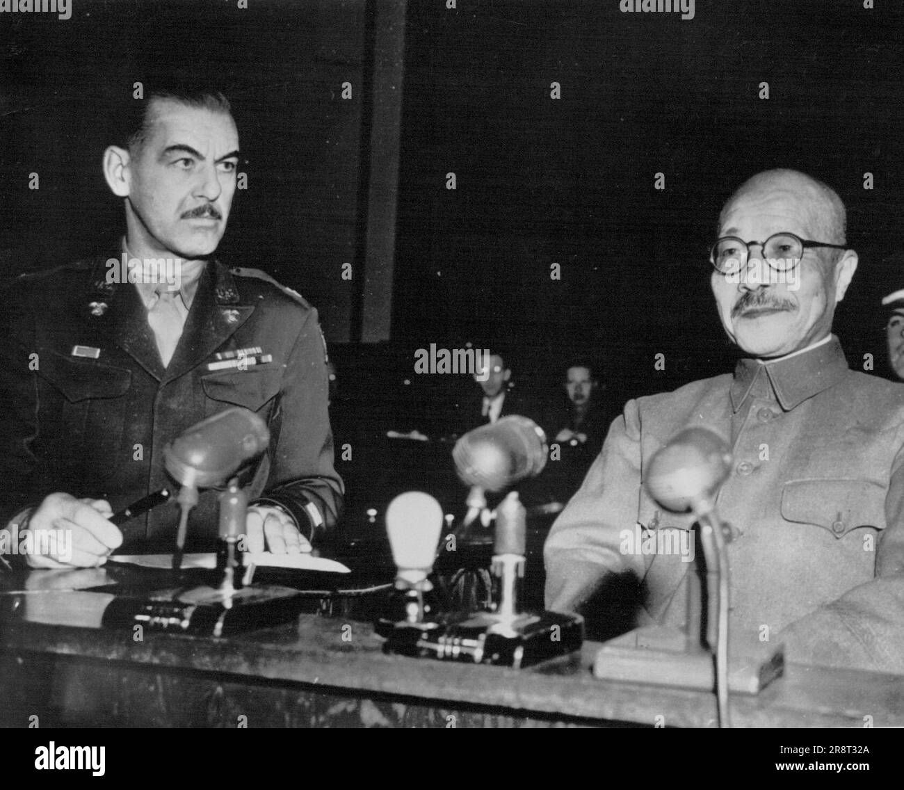 Tojo Sits in Witness Box at War Crimes Trial -- Japan's former premier, Hideki Tojo (right) seats self in witness box after being sworn in last Friday as a witness in his war crimes trial at Tokyo before the International Military Tribunal for the Far East. Capt. D.S. Van Meter, San Antonio, Texas, (left) marshal of the Tribunal court, administered the oath. December 29, 1947. (Photo by AP Wirephoto). Stock Photo