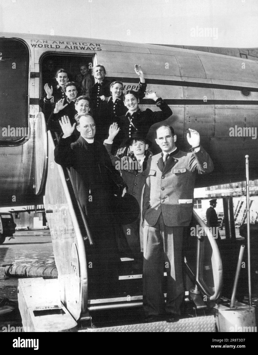 Nine members of the Trapp family, famed Austrian choral group are shown as they prepared to board a plane at New York for a concert tour of Latin American countries. The group is composed of Mrs. Maria Trapp, widow of an Austrian naval hero of World War I, Baron Gerose von Trapp; her daughters, Agatha, Hedwig, Martina, Maria and Eleanore; her sons, Werner and Johannes, and the family's priest-conductor, the Rev. Franz Wasner. February 6, 1955. (Photo by Associated Press Photo). Stock Photo