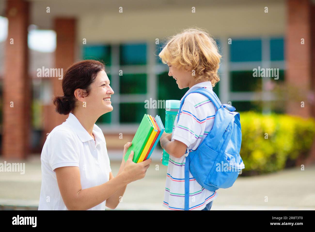 Mother bringing child to school. Parents pick up little boy after class